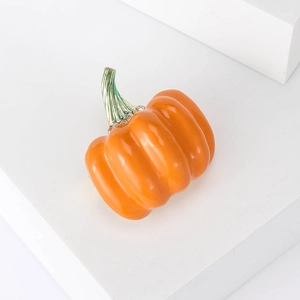 Cartoon pumpkin brooch with orange enamel and rhinestones on a white display stand