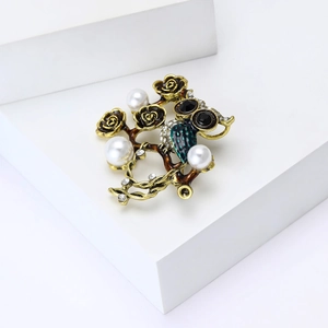 Détail d'une broche hibou vintage avec émail, roses et perles sur un support géométrique