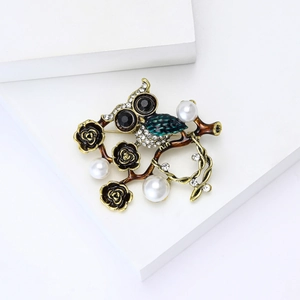 Détail de la broche hibou en émail vert, perles blanches et strass brillants sur métal