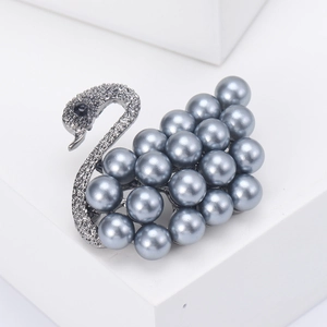 Macro view of gunmetal swan brooch featuring grey pearls and dark micro-pave crystals