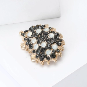 Macro detail of alloy hedgehog brooch with black and milky rhinestones in gold plating