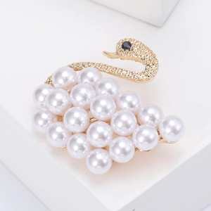 Detailed view of swan brooch with white pearls, golden metal neck and black gemstone eye
