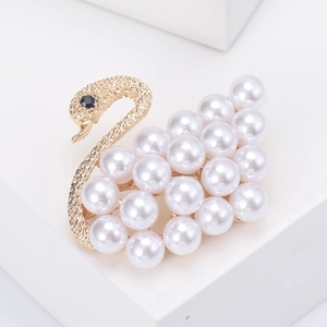 Detail of golden swan brooch featuring matte metal neck and white pearl embellishments
