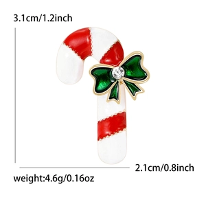Christmas candy cane brooch with red white enamel and a green bow on white background