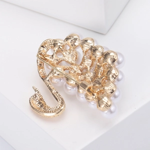 Detail view of the golden swan brooch back showing the pin fastener and metal hollow pattern