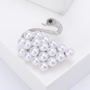 Close-up of elegant swan brooch featuring white pearls and silver metal with crystals