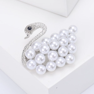 Detailed view of silver swan brooch with white pearls and sparkling crystals