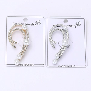 Detailed macro view of gold and silver ear cuffs with pearls and shimmering rhinestones