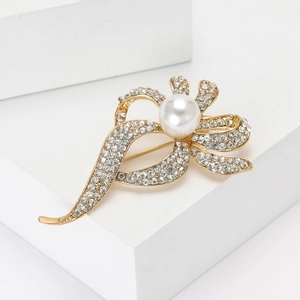 Broche ruban dorée élégante avec perle blanche et strass sur socle géométrique