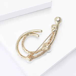 Elegant hollow gold brooch with pearl accents and artistic silhouette on a white block