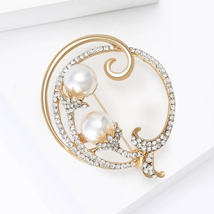 Détail d'une broche dorée ornée de grandes perles et de strass en cristal brillants