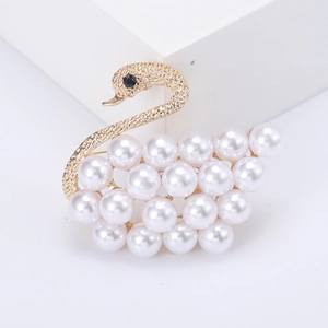 Elegant gold swan brooch featuring white pearls and matte finish on white platform