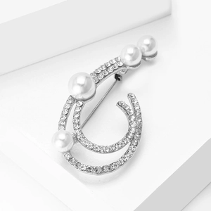 Close-up of elegant silver brooch with sparkling rhinestones and white pearls
