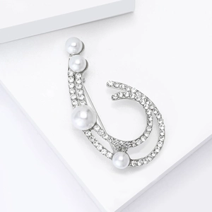 Detailed close-up of a silver-tone brooch featuring elegant pearls and sparkling rhinestones