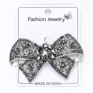 Macro shot of gun-black bow brooch with grey rhinestones on jewelry display card