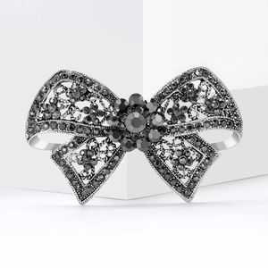 Elegant gun black bow brooch with dark crystals and lace metalwork on white background