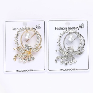 Detail of floral brooches with shimmering rhinestones and large round pearls in gold and silver