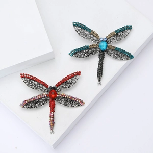 Vintage alloy dragonfly brooch set with red and blue rhinestones on white display