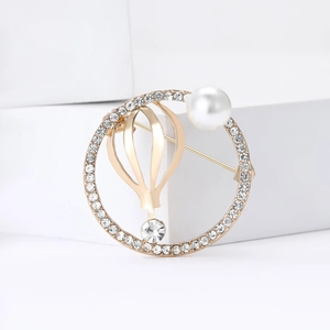 Elegante gouden luchtballon broche met fonkelende steentjes en een witte parel accent