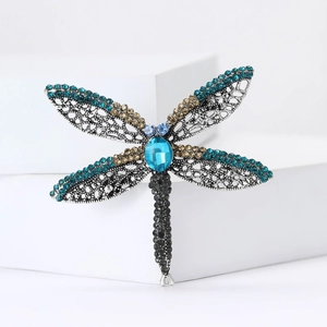 Vintage dragonfly brooch with antique silver finish, blue crystals, and hollow filigree