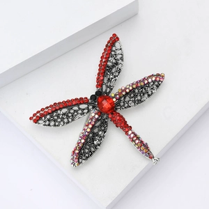 Macro shot of silver dragonfly brooch with red rhinestones and intricate hollow metalwork