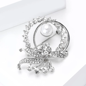 Detailed close-up of a silver flower brooch with white pearl and sparkling rhinestones