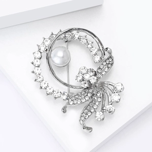 Close-up of silver-tone floral brooch with large white pearl and sparkling rhinestones