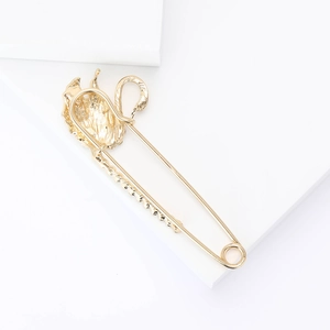 Detail view of a luxury swan-shaped safety pin brooch with golden alloy and rhinestones