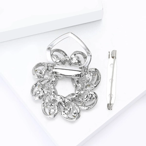 Macro detail of silver floral silk scarf buckle and rhinestone brooch pin attachment