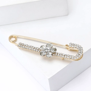 Détail d'une broche épingle de nourrice fleur dorée avec strass sur fond blanc