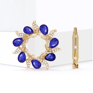 Floral wreath brooch with blue teardrop stones and rhinestones on a gold alloy base