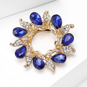 Detail view of flower wreath brooch with blue teardrop crystals and gold finish