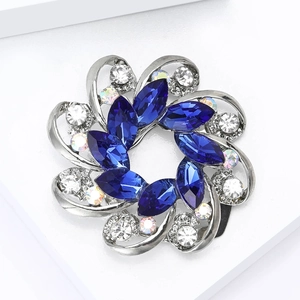 Detailed macro view of a silver floral brooch with blue gems and crystal rhinestones