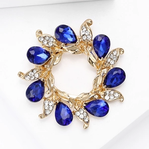 Macro detail of floral brooch featuring blue drop-shaped gems and white rhinestones