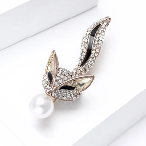 Vue détaillée d'une broche renard dorée ornée de strass brillants et d'une perle blanche