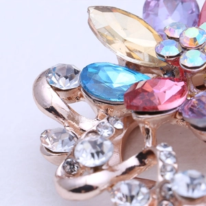 Détail macro d'une broche en or rose avec des pierres précieuses et strass colorés