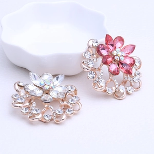 Détail macro d'une broche florale et d'un anneau de foulard en strass rose et cristal