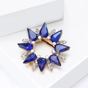 Detailed macro view of luxury sunburst scarf clip with deep blue drop-shaped crystals