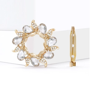 Detail view of flower-shaped golden brooch with crystals and secure pin clasp mechanism