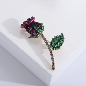 Elegante spilla a rosa con cristalli neri e verdi su un supporto bianco chic