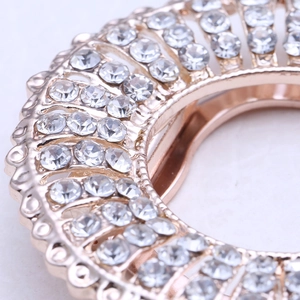 Macro detail of sparkling rhinestones on golden floral scarf clip brooch jewelry piece
