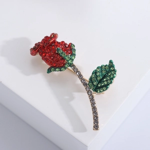 Elegante spilla a rosa con cristalli rossi e verdi su piattaforma bianca