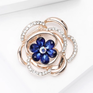 Detail of rose gold flower brooch featuring deep blue crystals and sparkling rhinestones