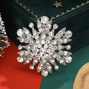 Elegant silver snowflake brooch with sparkling rhinestones on festive velvet background