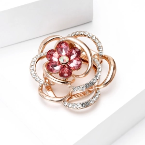 Close-up of rose gold flower brooch with pink pear-cut crystals and sparkling white rhinestones