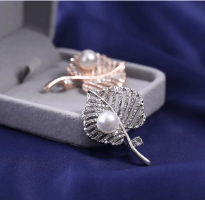 Macro detail of leaf-shaped pearl brooch with sparkling pavé cubic zirconia settings