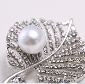 Macro shot of silver leaf brooch with sparkling pavé rhinestones and a lustrous pearl
