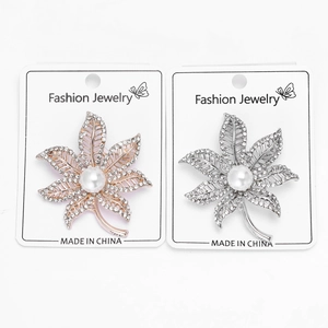 Detailed view of maple leaf brooches with white rhinestones and a central pearl