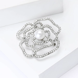 Dettaglio della spilla a camelia argentata con strass scintillanti e una perla centrale