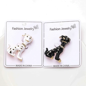 Detalle de broches de esmalte con forma de perro blanco y negro con pedrería en cartón